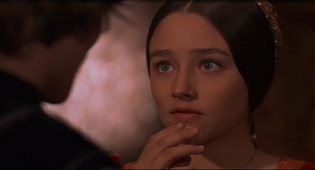 Movie still from “Romeo and Juliet” (1968), directed by Franco Zeffirelli – A young woman looking at the camera while holding her hand under her chin; Close Up shot, Over the shoulder angle