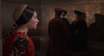Movie still from “Romeo and Juliet” (1968), directed by Franco Zeffirelli – A woman in a red dress looking to her left; Close Up shot, Over the shoulder angle