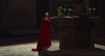 Movie still from “Romeo and Juliet” (1968), directed by Franco Zeffirelli – A woman in a red dress standing in front of a fountain; Wide shot, Low angle