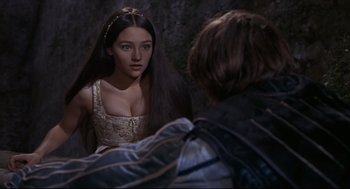 Movie still from “Romeo and Juliet” (1968), directed by Franco Zeffirelli – A woman in a white dress looking at a man in a black jacket; Medium shot, Over the shoulder angle