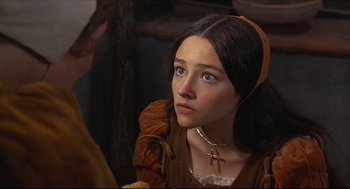 Movie still from “Romeo and Juliet” (1968), directed by Franco Zeffirelli – A young woman in a brown dress looking to her left; Close Up shot, Over the shoulder angle