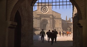 Movie still from “Romeo and Juliet” (1968), directed by Franco Zeffirelli – A group of people walking in front of an old building; Extreme Wide shot, High angle
