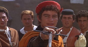 Movie still from “Romeo and Juliet” (1968), directed by Franco Zeffirelli – A young man wearing a red hat and holding a sword; Close Up shot, Over the shoulder angle