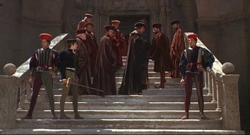 Movie still from “Romeo and Juliet” (1968), directed by Franco Zeffirelli – A group of men in medieval garb standing on some steps; Wide shot, High angle