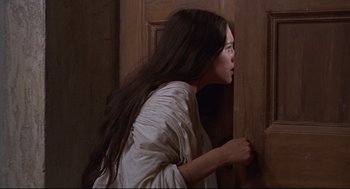 Movie still from “Romeo and Juliet” (1968), directed by Franco Zeffirelli – A woman in a white dress looking out of a door; Close Up shot, Over the shoulder angle