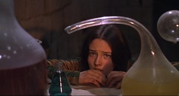 Movie still from “Romeo and Juliet” (1968), directed by Franco Zeffirelli – A woman sitting at a table looking at the camera; Medium shot, High angle