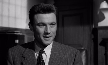 Movie still from “Room at the Top” (1958), directed by Jack Clayton – Black and white photograph of a man wearing a suit and tie; Close Up shot, Low angle