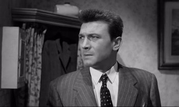 Movie still from “Room at the Top” (1958), directed by Jack Clayton – Black and white photograph of a man wearing a suit and tie; Close Up shot, Low angle