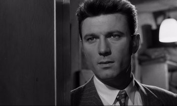 Movie still from “Room at the Top” (1958), directed by Jack Clayton – Black and white photograph of a man in a suit; Close Up shot, Low angle