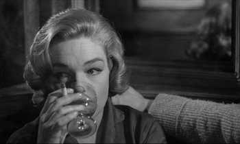 Movie still from “Room at the Top” (1958), directed by Jack Clayton – A black and white photo of a woman drinking a glass; Close Up shot, Over the shoulder angle