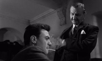 Movie still from “Room at the Top” (1958), directed by Jack Clayton – An older man smoking a cigarette next to a younger man; Medium shot, Over the shoulder angle