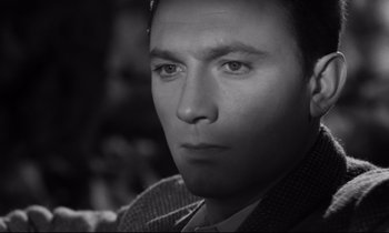 Movie still from “Room at the Top” (1958), directed by Jack Clayton – Black and white photograph of a man in a suit and tie; Close Up shot, High angle