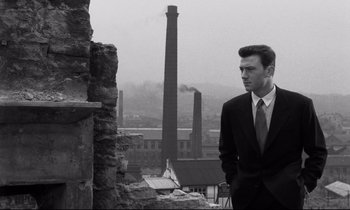 Movie still from “Room at the Top” (1958), directed by Jack Clayton – A man in a suit standing in front of a building; Medium shot, Low angle