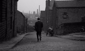 Movie still from “Room at the Top” (1958), directed by Jack Clayton – A black and white photo of a man walking down a street; Extreme Wide shot, High angle