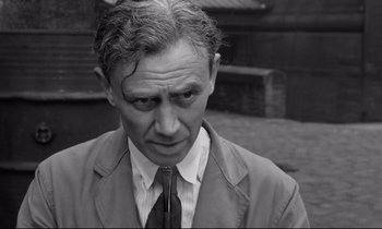 Movie still from “Room at the Top” (1958), directed by Jack Clayton – An older man wearing a suit and tie looking at the camera; Close Up shot, High angle