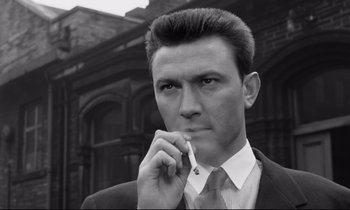 Movie still from “Room at the Top” (1958), directed by Jack Clayton – Black and white photograph of a man smoking a cigarette; Close Up shot, Low angle