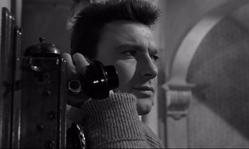 Movie still from “Room at the Top” (1958), directed by Jack Clayton – A black and white photo of a man holding a camera; Close Up shot, Low angle