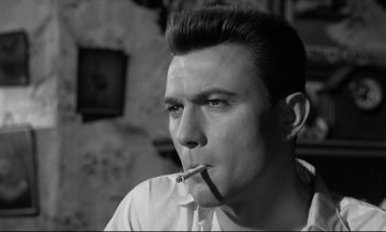 Movie still from “Room at the Top” (1958), directed by Jack Clayton – A black and white photo of a man smoking a cigarette; Close Up shot, Low angle