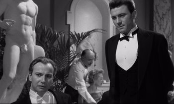 Movie still from “Room at the Top” (1958), directed by Jack Clayton – Two men and a woman in tuxedos in a room; Medium shot, Over the shoulder angle