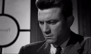 Movie still from “Room at the Top” (1958), directed by Jack Clayton – Black and white photograph of a man in a suit; Close Up shot, Low angle