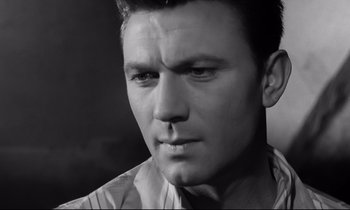 Movie still from “Room at the Top” (1958), directed by Jack Clayton – Black and white photograph of a man looking at the camera; Close Up shot, High angle