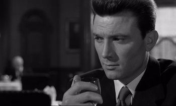 Movie still from “Room at the Top” (1958), directed by Jack Clayton – A black and white photo of a man holding a cell phone; Close Up shot, Over the shoulder angle