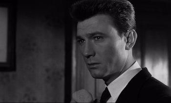 Movie still from “Room at the Top” (1958), directed by Jack Clayton – Black and white photograph of a man in a suit and tie; Close Up shot, Low angle