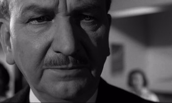 Movie still from “Room at the Top” (1958), directed by Jack Clayton – Black and white photograph of a man with a mustache; Close Up shot, Low angle