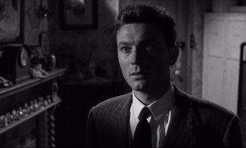 Movie still from “Room at the Top” (1958), directed by Jack Clayton – Black and white photograph of a man wearing a suit and tie; Close Up shot, Low angle