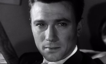Movie still from “Room at the Top” (1958), directed by Jack Clayton – Black and white photograph of a man in a suit and tie; Close Up shot, Low angle