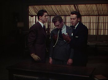 Movie still from “Rope” (1948), directed by Alfred Hitchcock – A group of men standing next to each other in front of a table; Medium shot, High angle