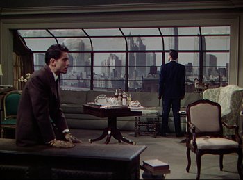 Movie still from “Rope” (1948), directed by Alfred Hitchcock – A man in a suit and tie standing in front of another man in a suit and tie in front of a large window; Wide shot, Over the shoulder angle