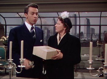 Movie still from “Rope” (1948), directed by Alfred Hitchcock – A man and a woman holding a box in a room; Medium shot, Over the shoulder angle