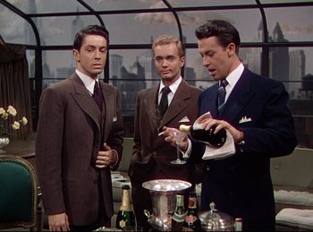 Movie still from “Rope” (1948), directed by Alfred Hitchcock – A group of men in suits standing around a table; Medium shot, Low angle