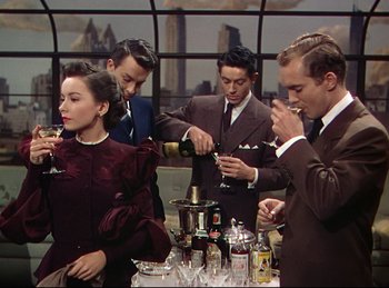 Movie still from “Rope” (1948), directed by Alfred Hitchcock – A group of people standing around a table with drinks; Medium shot, High angle