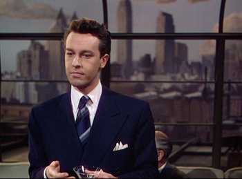 Movie still from “Rope” (1948), directed by Alfred Hitchcock – A man in a suit and tie holding a glass; Medium shot, Over the shoulder angle