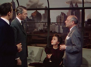Movie still from “Rope” (1948), directed by Alfred Hitchcock – A group of people standing around each other in front of a window; Medium shot, Over the shoulder angle