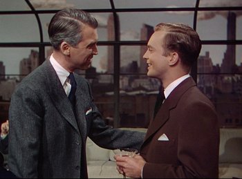 Movie still from “Rope” (1948), directed by Alfred Hitchcock – Two men in business suits are shaking hands in front of a window; Medium shot, Over the shoulder angle