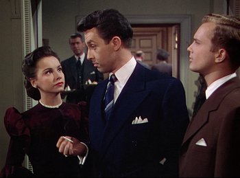 Movie still from “Rope” (1948), directed by Alfred Hitchcock – A group of people standing next to each other in a room; Medium shot, Over the shoulder angle