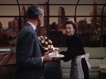 Movie still from “Rope” (1948), directed by Alfred Hitchcock – An older woman serving a cake to an older man; Medium shot, Over the shoulder angle