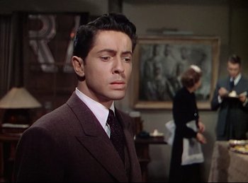 Movie still from “Rope” (1948), directed by Alfred Hitchcock – A man wearing a suit and tie standing in front of a woman; Medium shot, Over the shoulder angle