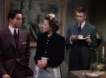 Movie still from “Rope” (1948), directed by Alfred Hitchcock – A group of people standing next to each other in a room; Medium shot, Over the shoulder angle