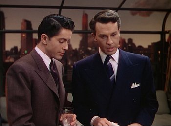 Movie still from “Rope” (1948), directed by Alfred Hitchcock – Two men in business suits looking at a piece of paper; Medium shot, Over the shoulder angle