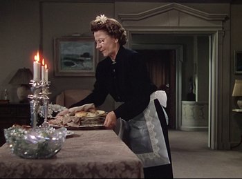 Movie still from “Rope” (1948), directed by Alfred Hitchcock – An older woman standing at a dining room table; Medium shot, High angle