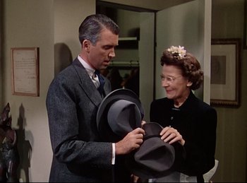 Movie still from “Rope” (1948), directed by Alfred Hitchcock – A man and a woman holding hats in a room; Medium shot, Over the shoulder angle