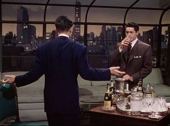 Movie still from “Rope” (1948), directed by Alfred Hitchcock – A man in a suit is drinking a drink; Medium shot, Over the shoulder angle