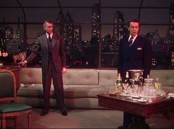 Movie still from “Rope” (1948), directed by Alfred Hitchcock – Two men in suits stand in front of a bar; Wide shot, Over the shoulder angle