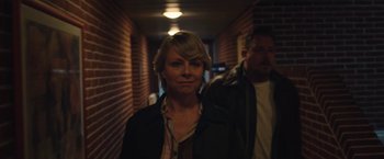 Movie still from “Rose” (2022), directed by Niels Arden Oplev – A woman standing in a hallway with a man standing behind her; Close Up shot, Over the shoulder angle