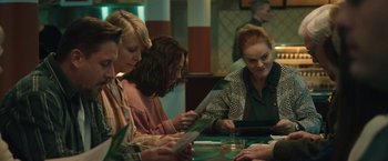 Movie still from “Rose” (2022), directed by Niels Arden Oplev – A group of people sitting at a table looking at papers; Medium shot, Over the shoulder angle