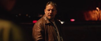 Movie still from “Rose” (2022), directed by Niels Arden Oplev – A man in a brown leather jacket standing in the dark; Close Up shot, Low angle